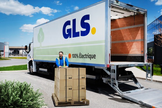 Un chauffeur livre une palette de boîtes près d'un camion GLS 100 % électrique.