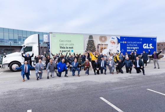 Camion des fêtes GLS avec un groupe d'employés s'amusant devant.