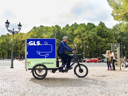 GLS van driving over a bridge in a town