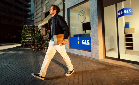 Man walks out of GLS pick-up point with package in hand