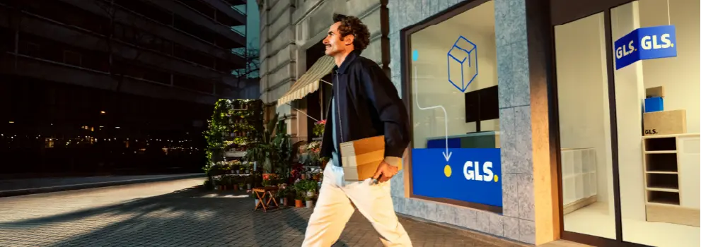 Man walks out of GLS pick-up point with package in hand
