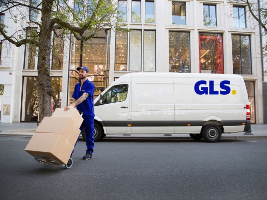 GLS courier delivering and picking a parcel to and from a shop